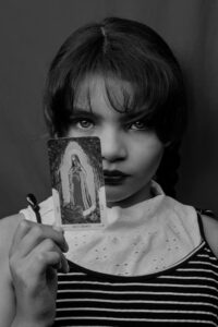 A black and white portrait of a young girl holding a tarot card, exuding mystery and intrigue.